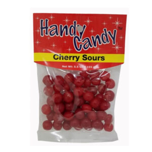 A clear plastic bag labeled Handy Candy CHERRY SOURS contains small round red candies. The red and yellow package with white stars lists a net weight of 5.5 oz (155 g).